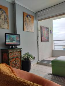 sala de estar con TV y ventana en Departamento en Reñaca, en Viña del Mar