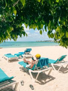 a man sitting on a beach with a laptop at Hotel Cocoplum Beach in San Andrés