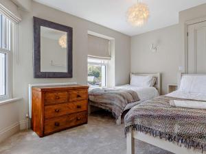 a bedroom with two beds and a dresser and a mirror at 4 Bed in Fowey 82152 in Fowey