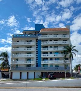 un edificio alto y blanco con palmeras delante en "Condominio Américas", en Boca del Río