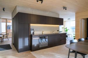 a kitchen with dark wood cabinets and a table at Mondholz Ferienwohnung in Andermatt
