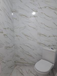 a white bathroom with a toilet and marble wall at GuestHouse "ERKIN" in Karakol +75 photos