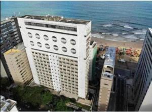a tall white building next to the ocean at Flat vista mar Boa Viagem in Recife