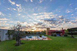 a yard with two white chairs and a pool at Estancia Yolanda C1 - by Inside in Ciudad Lujan de Cuyo