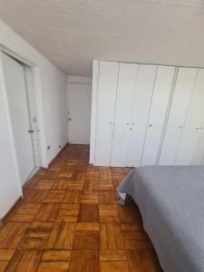 una camera con pavimenti in legno, armadi bianchi e un letto di Las condes, Amplia habitación con baño privado a Santiago