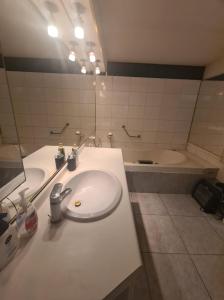 a bathroom with a white sink and a tub at Las condes, Amplia habitación con baño privado in Santiago
