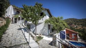 a white house with a tree next to a street at Ambelikos Traditional Agrohotel in Potamitissa