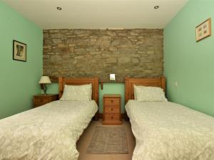 two beds in a room with a stone wall at 4 Bed in Whaley Bridge PK534 in Whaley Bridge