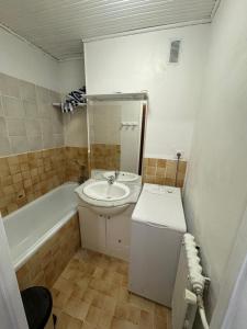 uma pequena casa de banho com um lavatório e uma banheira em Appartement Tignes - Quartier Calme - 2 chambres - 3 Télévisions - Netflix & Wifi inclus em Tignes