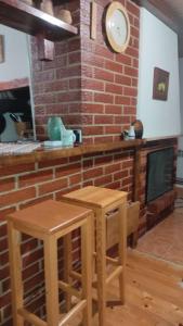 a kitchen with two stools and a fireplace with a clock at Vikendica Mašan in Pale