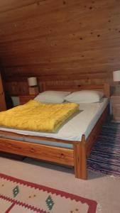 a bed with a wooden bed frame in a room at Vikendica Mašan in Pale