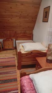 two beds in a room with wooden walls at Vikendica Mašan in Pale