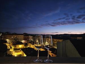 - deux verres à vin assis au-dessus d'un balcon la nuit dans l'établissement Cuencaloft Ático Encantado Deluxe con Terraza, à Cuenca