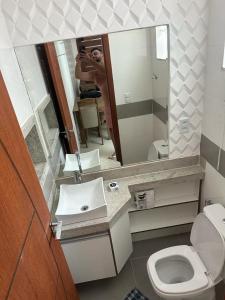 a man taking a picture of a bathroom with a mirror at Apartamento Porto Villa dos Diamantes 22 in Porto Seguro