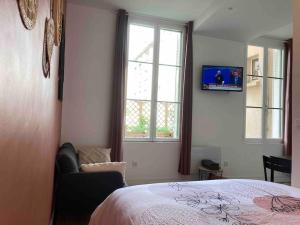 a bedroom with a bed and a tv and two windows at Studio N1 plein centre ville in Rouen