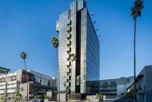 a tall glass building with palm trees in front of it at Kasa Sunset Los Angeles in Los Angeles