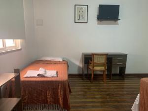 a bedroom with a bed and a desk with a computer at Casa do Sol Fortaleza in Fortaleza
