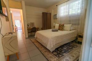 1 dormitorio con cama, escritorio y ventana en Casa Pina Suave #1, en Rincón
