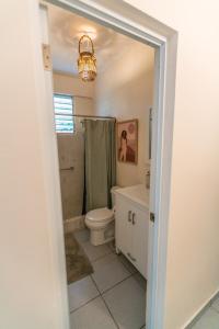 y baño con aseo, lavabo y lámpara de araña. en Casa Pina Suave #1, en Rincón