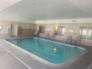 a large pool in a hotel with chairs and tables at Baymont by Wyndham Springfield I-44 in Springfield