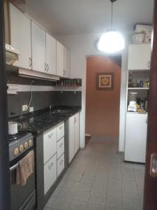 a kitchen with white cabinets and a stove top oven at Posada de la Costa in Villa Carlos Paz