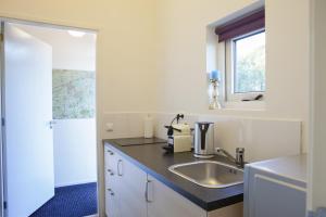 a white kitchen with a sink and a window at Logement de Kaap in Terheijl