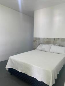 sypialnia z dużym białym łóżkiem w pokoju w obiekcie Pousada Esmeralda w mieście Maragogi