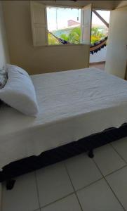 Bett in einem Zimmer mit Kissen und Fenster in der Unterkunft Pousada Esmeralda in Maragogi