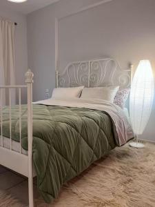 a bedroom with a bed with a green blanket and a lamp at Διαμέρισμα «Εξοχή» στο Καλπάκι in Kalpákion