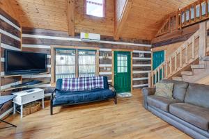 a living room with a couch and a tv at Rustic North Carolina Cabin with Fire Pit and Porch in Sylva