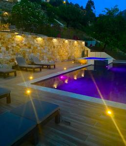 a swimming pool with lights and a stone wall at Gîte A Funtana in Manso