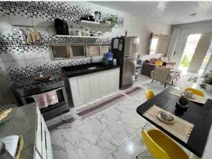 a kitchen with a stove and a table with yellow chairs at Aconchegante e charmosa in Penedo