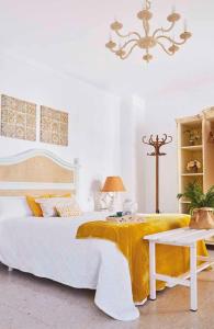 ein Schlafzimmer mit einem großen weißen Bett mit einer gelben Decke in der Unterkunft El Patio del Limonero in Écija