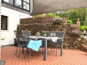 een tafel en stoelen op een patio met een stenen muur bij Garden view Apartment in Sauerland with Terrace in Madfeld