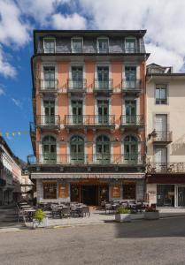 a tall orange building with tables in front of it at Hôtel Le Bois Joli in Cauterets