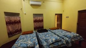 two beds in a room with two windows at Bequest Stays Celebration in Puri
