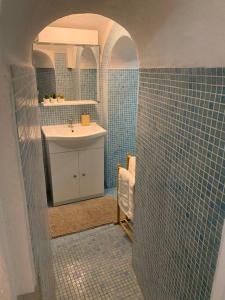 a bathroom with a sink and a blue tiled wall at Studio Perle de Menton in Menton