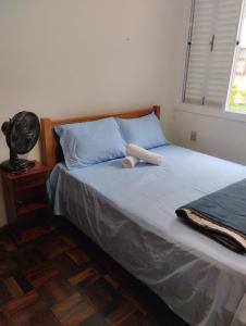 a bedroom with a bed with blue pillows and a fan at Apartamento 2 quartos in Pelotas
