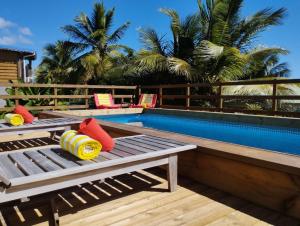 a swimming pool with two wooden benches next to a pool at Villa BABYLAS in Sainte-Anne
