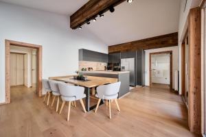 - une cuisine avec une table en bois et des chaises blanches dans l'établissement Appartement Emma, à Eben im Pongau