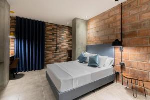 1 dormitorio con cama blanca y pared de ladrillo en Apartahotel Medellin, en Medellín