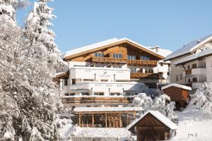 a ski lodge in the snow with trees at Hotel Garni Hubertushof in Fiss