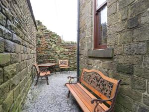 a patio with two benches and a table and a window at Old Bar House in Keighley