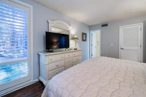 Schlafzimmer mit einem Bett, einem TV und einem Fenster in der Unterkunft 1341 Pelican Watch Villa in Seabrook Island