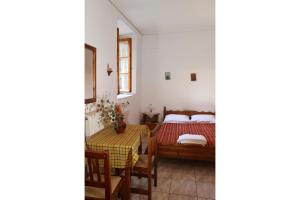 een slaapkamer met een bed en een tafel en stoelen bij Maleatis Apollo Guesthouse in Kosmás