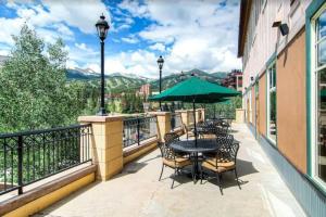 a balcony with a table with chairs and an umbrella at Hyatt Residence Club Main Street Station in Breckenridge