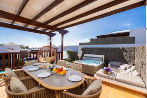 a patio with a table and chairs and a hot tub at Villa Saona in Playa Blanca