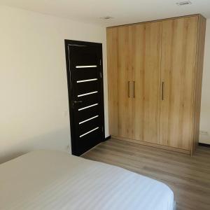 a bedroom with a bed and a wooden cabinet at S&T&A&R apartamentai in Panevėžys