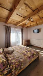 una camera con un grande letto e una TV a parete di Conacul din Pădure a Poiana Mărului