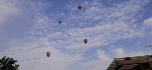 vier heteluchtballonnen vliegen in de lucht bij Cabaña EL SALTO DEL DUENDE in Carrión de los Céspedes